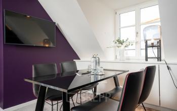 Moderner Konferenzraum mit schwarzem Tisch, vier Stühlen und großem Bildschirm in der Ludwigstraße 8, München Maxvorstadt. Ideal zum Büroraum mieten.